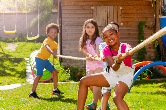 Group of diverse children pull rope in competition