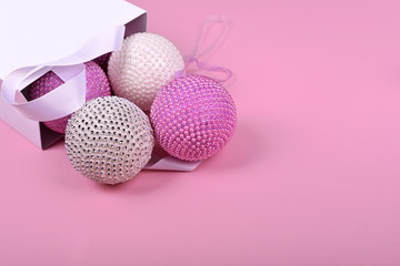 pink Christmas balls from a white package on a pink background