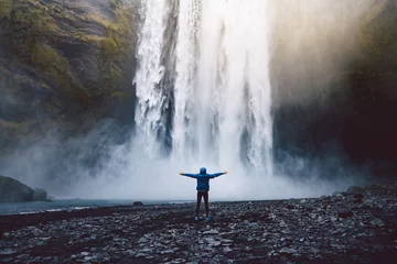 Foto auf Glas Eine Person, die die Schönheit des Skogafoss-Wasserfalls in Island bewundert © kbarzycki