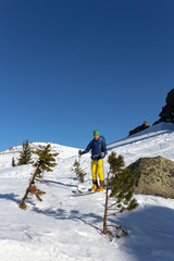 Young active man ski touring and staying at mountain peak background. ski tour. ski guy stands and walks in the mountains