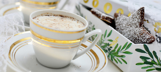 Cups of cocoa and homemade cookies in star shape on the festive table with gold elegant christams mood. Panoramic banner.