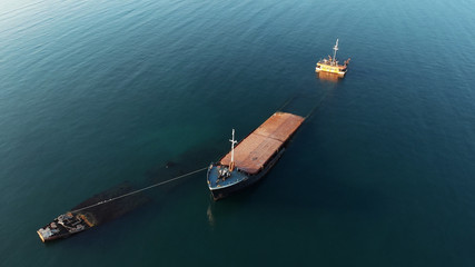 Aerial drone view of sunken cargo ship or tug boat near seaside. Shipwreck vessel with nose of ship...