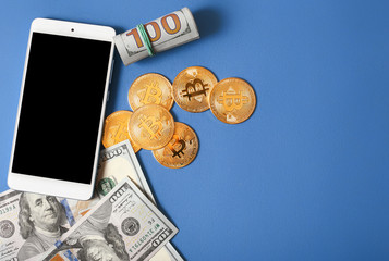 Bitcoins, money and smartphone on a blue background top view