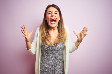 Young beautiful woman standing over pink isolated background celebrating mad and crazy for success...