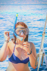 Jeune femme rousse remontant sur son bateau après une plongée avec masque et tuba en pleine mer...