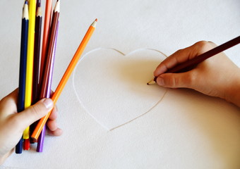 Multi-colored pencils. The child draws on white paper.