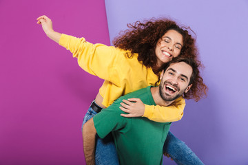 Portrait of happy smiling couple man and woman in colorful clothing having fun while doing...