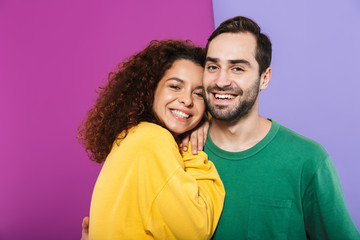 Portrait of brunette young couple man and woman in colorful clothing smiling and hugging together