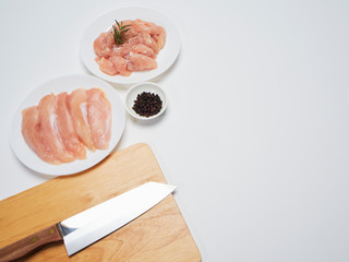 Fresh chicken tenderloin with wooden board, knife.