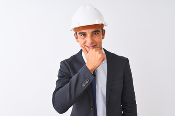 Young handsome architect man wearing suit and helmet over isolated white background looking confident at the camera with smile with crossed arms and hand raised on chin. Thinking positive.