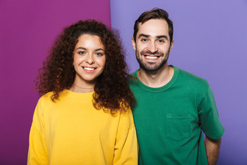 Portrait of young caucasian couple man and woman in colorful clothing smiling together at camera