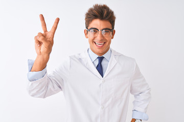 Young handsome sciencist man wearing glasses and coat over isolated white background smiling looking to the camera showing fingers doing victory sign. Number two.