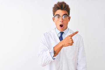 Young handsome sciencist man wearing glasses and coat over isolated white background Surprised...