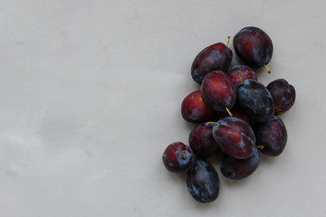 Plums on gray wooden background. Top view. Flat lay. Harvesting or healthy food concept.