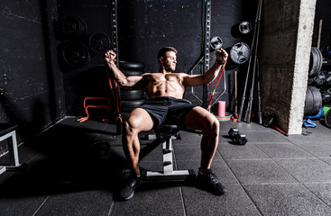 Young strong focused fit muscular man chest bench press stretching workout training in the gym with rubber for strength and good looking of muscles dark image real people training selective focus