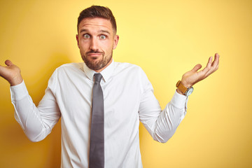 Young handsome business man wearing elegant white shirt over yellow isolated background clueless...