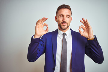 Young handsome business man over white isolated background relax and smiling with eyes closed doing meditation gesture with fingers. Yoga concept.