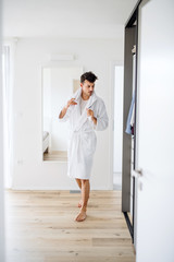 Fototapeta na wymiar Young man with bathrobe in the bedroom, a morning routine.
