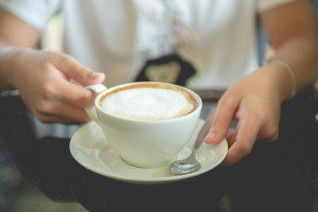 A cup of cappuccino in a woman's hand