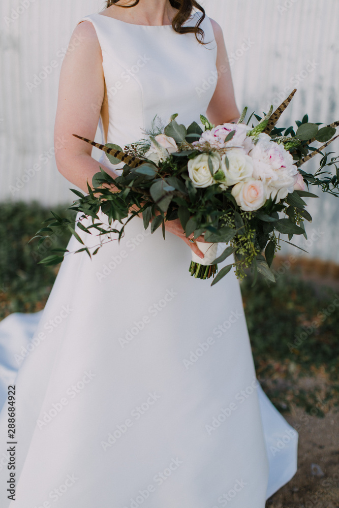 Wall mural Bride holding a bouquet outside 