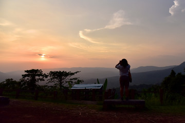 Landscape view of tourist woman shooting photo and enjoy with beautiful sunset view on hill