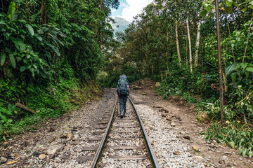 Naklejka na ściany i meble Back view of male hiker with backpack. Tourist man hiking along railroad to Machu Picchu, Peru