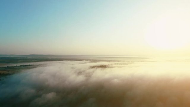 High aerial view of the large shiny sun over fluffy golden clouds. 4K.