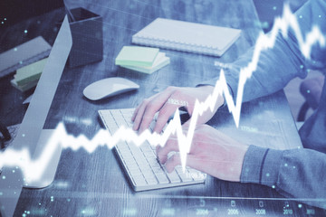 Stock graph with businessman typing on computer in office on background. Concept of analysis. Double exposure.