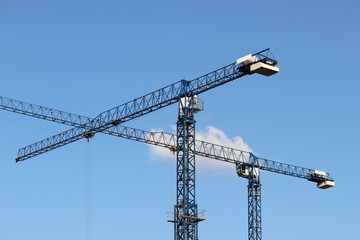 Two construction cranes on clear blue sky background. Concept of housing construction