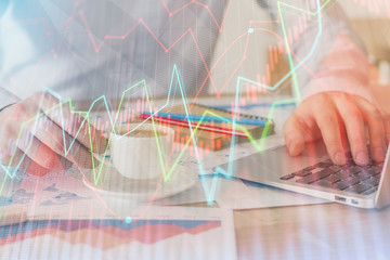 Forex graph with businessman working on computer in office on background. Concept of hardworking. Double exposure.