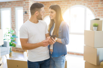 Young couple moving to a new house, using smartphone smiling very happy for new apartment