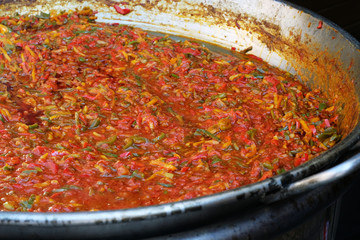 preparing the vegetable and spice base for delicious paella - traditional spanish food - on the street