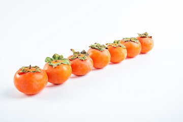 Row of red persimmons with fresh fruits on white background