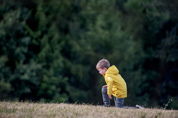 Side view of school child standing on field trip in nature, resting.