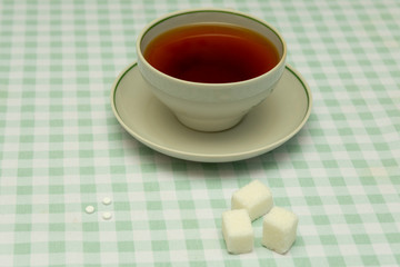 three small sweetener tablets replacing three teaspoons of sugar in hand for adding to a cup of tea