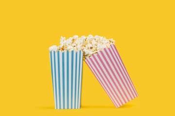 Popcorn palomitas de maíz en cajas celeste y rosa a rayas sobre un fondo amarillo brillante y aislado. Vista de frente y de cerca. Copy space