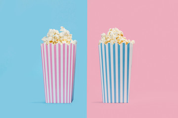 Popcorn palomitas de maíz en cajas de cartón reciclable con rayas sobre un fondo rosa y celeste...