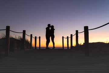 Silhouette of man and woman couple kissing at a beautiful sunset on the beach.