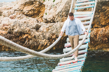 man walking by suspension bridge cross adriatic sea