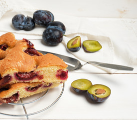 slices of biscuit plum cake on a white wooden board and fresh fruits