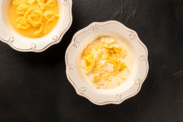 Tortellini served with broth and cream sauce, Italian food on a black background