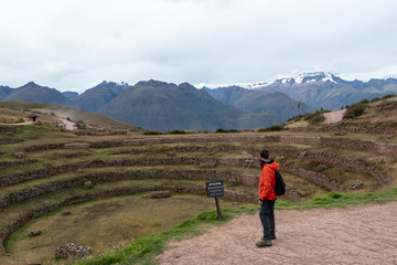 Young male tourist traveling alone in Sacred valley. Solo man hiker with backpack sightseeing inca ruins in Cusco region, Peru