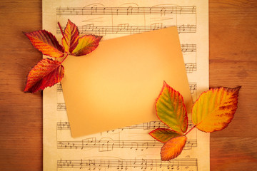 Autumn background with vibrant fall leaves with a card and sheet music, a design template for a flyer, invitation, or gift card with a place for text and logo