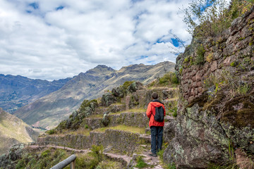 Young male tourist traveling alone in Sacred valley. Solo man hiker with backpack sightseeing inca ruins in Cusco region, Peru