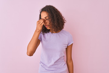 Young brazilian woman wearing t-shirt standing over isolated pink background tired rubbing nose and eyes feeling fatigue and headache. Stress and frustration concept.