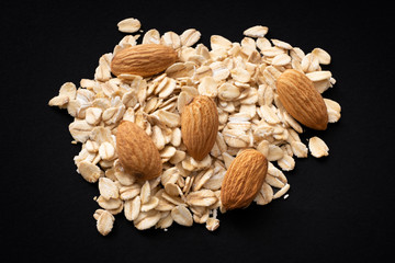 Pile of oatmeal and almonds. Isolated on black background.