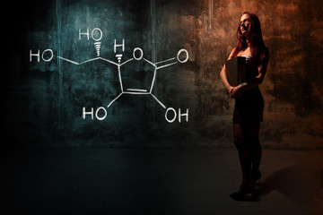 Sexy girl or secretary or female student presenting handdrawn chemical formula of Vitamin C