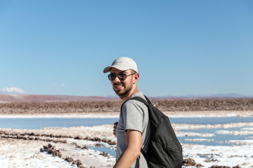 Young caucasian man looking at camera with lagunas Escondidas of Baltinache in Atacama Desert, Chile, South America