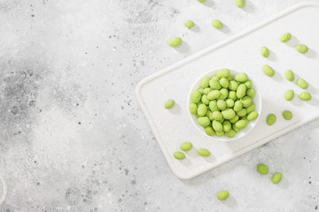 Peanuts in wasabi in a white plate on a light table. Top view