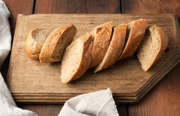 sliced rye flour baguette on a wooden cutting board